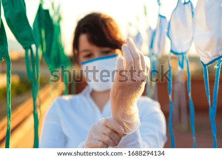Young girl assistant cleaning masks in these days of pandemic. Also tired and sad.