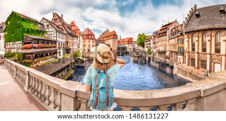 Young girl with backpack standing on a bridge over d Ill river in Strasbourg, France