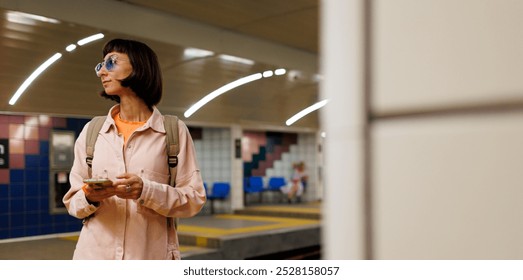 Young girl with a backpack uses a smartphone in the subway. girl waiting for a train. girl in the subway. - Powered by Shutterstock