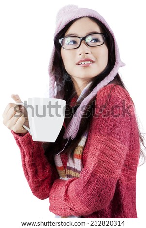 Young girl with beautiful face enjoy a hot drink while wearing a knitted clothes and hat, isolated on white