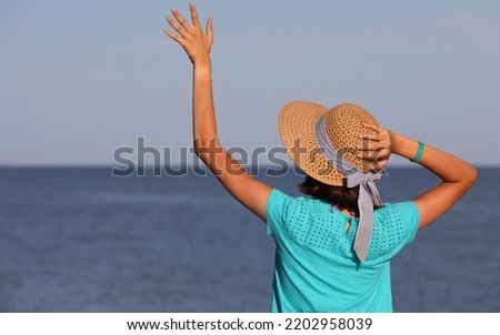 young girl with big straw hat by the sea during summer vacation