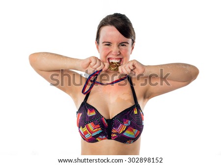 Young girl in bikini biting a gold medal isolated on white background