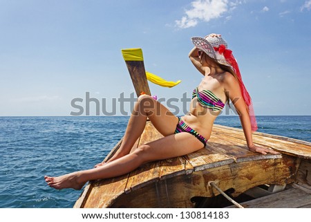 young girl in bikini sitting on Thai Longtail boat
