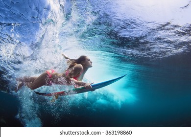 Young girl in bikini    surfer and surf board dive underwater and fun under big ocean wave  Family lifestyle  people water sport lessons   beach swimming activity summer vacation and child