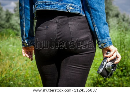 A young girl in black pants holds an old camera