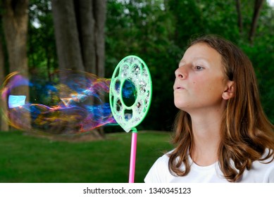 Young Girl Blowing Giant Bubble Outside