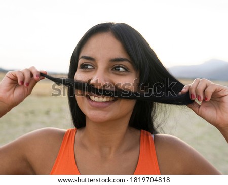 young girl blowing her hair like a mustache