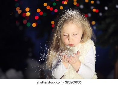 Young girl blowing snow flakes on the outside