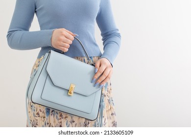 young girl in blue blouse  and pleated skirt with blue handbag on white background