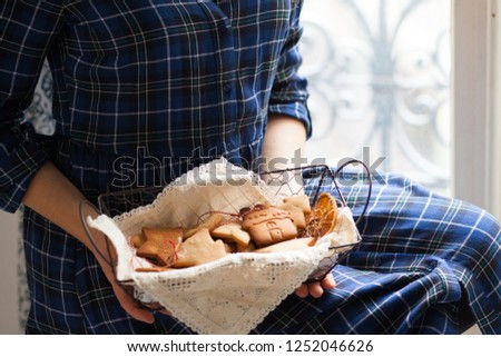 Young girl in blue dress holds in her hands a rustic basket of homemade gingerbread cookies. Family time preparing for christmas. Home holiday atmsophere, festive mood