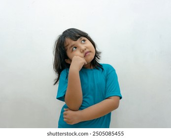 A young girl in a blue dress, thoughtfully looking upward, as if deep in thought. - Powered by Shutterstock