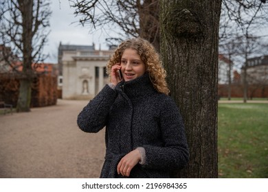 A Young Girl With Braces Makes A Phone Call While In A Park In The Open Air In Winter