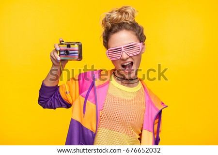 Young girl in bright sportive clothing and sunglasses posing with photo camera. 