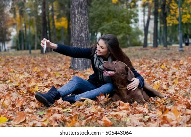 young girl with a brown labrador in the autumn park, make selfie photo