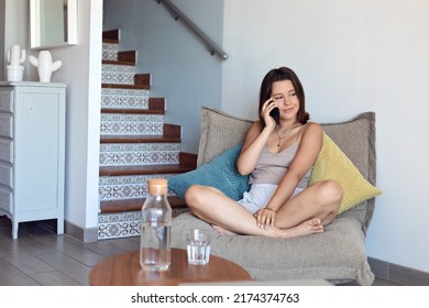 Young Girl In Casual Summer Outfit Talking On The Phone At Home. Comfort And Cozy Girlish Time. Smiling, Enjoying Relaxing Atmosphere Indoors 