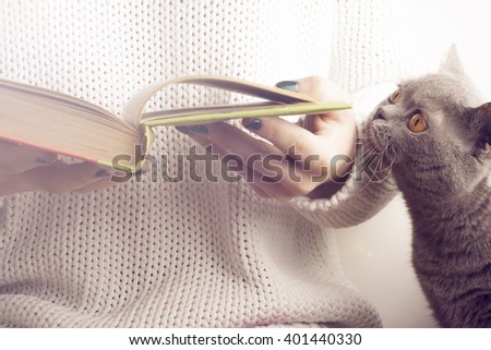 young girl and a cat reading  an  open book . old book. Books and reading are essential for self improvement, gaining knowledge and success in our careers, business and personal lives.