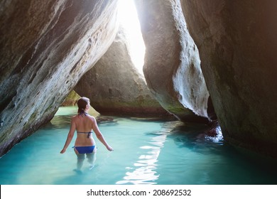 Young Girl At Cave Covered With Water At The Baths Beach Area Major Tourist Attraction At Virgin Gorda, British Virgin Islands With White Sand, Turquoise Ocean And Huge Granite Boulders