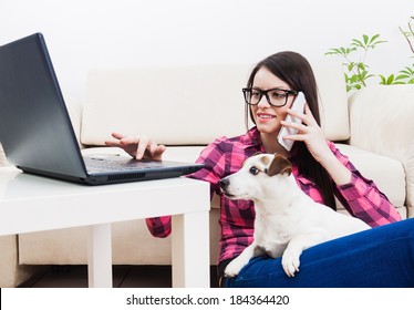 Young Girl Chatting On Mobile Phone, Using Computer  With Pet Dog In Lap