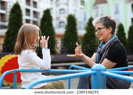 A young girl child and happy woman proficient in sign language communicates joyfully, fostering connections in the city.