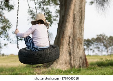 Young girl child on tire tyre outdoors swing hanging from a tree 