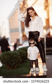 Young girl and child in white shirts and black sunglasses against the background of skyscrapers