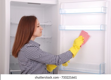 Young Girl Cleaning Empty Fridge With A Sponge. Beautiful Young Girl Near The Fridge.