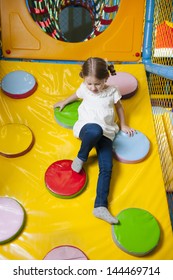 Young Girl Climbing Down Ramp In Soft Play Center