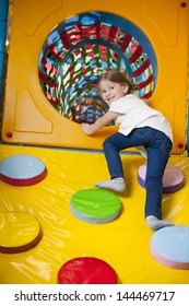 Young Girl Climbing Up Ramp Into Tunnel At Soft Play Center