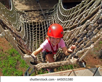 Young Girl Climbs On A High Ropes Course                               