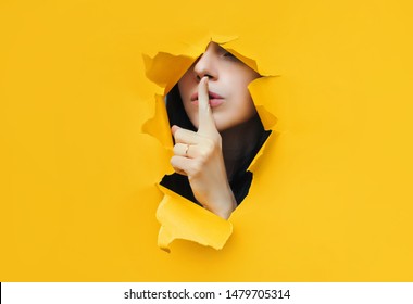 A young girl closes her lips with her index finger,making it clear to the viewer that you need to observe silence,keep a secret and not say too much. Censorship and harassment of freedom of speech. - Shutterstock ID 1479705314