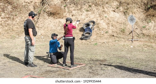 Young girl with coach on tactical gun training classes. Woman with weapon. Outdoor Shooting Range
