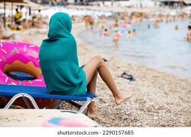 Young girl covered with microfibre beach towel, wrapped in quick absorbent dry towel