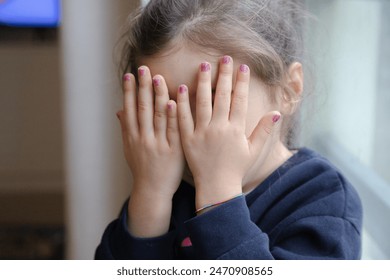 A young girl covers her face with her hands, showing off her freshly painted pink nails. Her playful gesture and shy demeanor capture the innocence and creativity of childhood. - Powered by Shutterstock