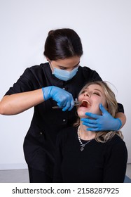 Young girl Dentist performs tooth extraction with tongs in a young girl patient on a light background - Shutterstock ID 2158287925