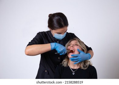 Young girl Dentist performs tooth extraction with tongs in a young girl patient on a light background - Shutterstock ID 2158288519