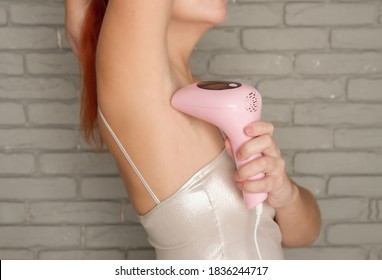 a young girl does her own armpit depilation with a personal laser depilator at home