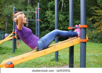 A young girl doing abdominal crunches on the outdoor sports ground