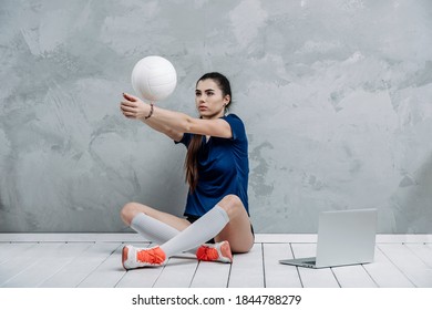 Young girl doing exercises with volleyball ball watching online tutorials on laptop. A sports coach leads an online lesson. Online workout concept. Vintage color filter - Powered by Shutterstock