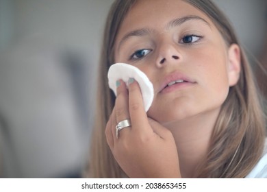 young girl doing facial cleansing in front of a mirror - Shutterstock ID 2038653455