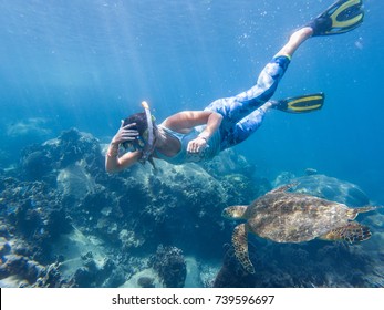 Young girl doing snorkeling. Next floating turtle. Koh Tao, Thailand.