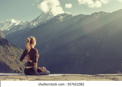 Young Girl Doing Yoga Fitness Exercise Outdoor In Beautiful Mountains Landscape. Morning Sunrise, Namaste Lotus Pose. Meditation And Relax