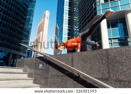 Young girl doing yoga outdoors in a city on the background of skyscrapers