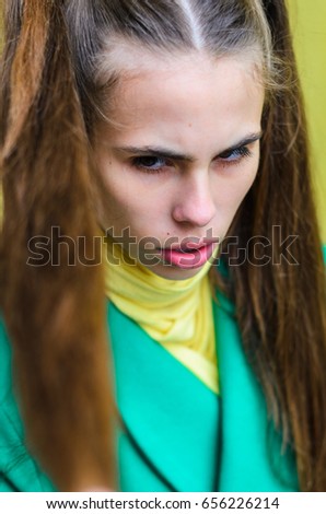 a young girl dressed in a green coat and yellow dress. Pure colors in the photo. girl fun fooling around .