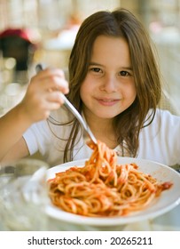 young girl eating spaghetti in restaurant