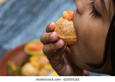 Young Girl Eating Spicy Pani Puri Golgappe Served With Yogurt, Chat Item, India. Snacks Eaten With Tangy Tamarind Water And Potato Stuffing. Kid Enjoying North Indian Street Food Delhi, Mumbai.