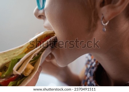 Young  girl eating tortilla with meat and vegetables, mexican traditional snack concept
