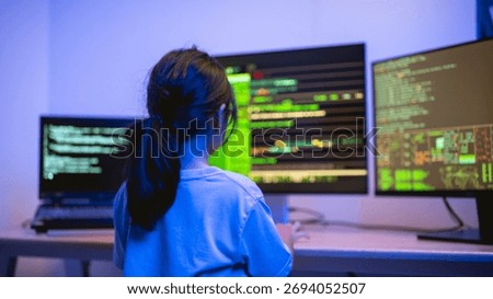 Young Girl Engaged in Coding Activity in a Dark Room with Multiple Computer Monitors Displaying Lines of Code and Data Visualization