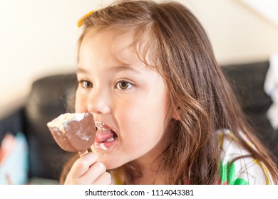 A young girl enjoying a chocolate ice lollipop