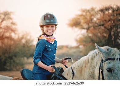Young girl enjoying a horse back ride in the golden afternoon light. Riding on a white horse dressed in a denim shirt. - Powered by Shutterstock