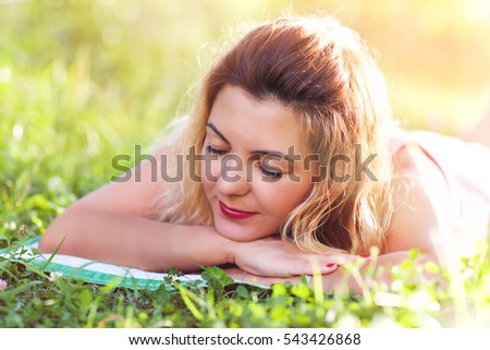A young girl of the European appearance lying on the grass, eyes closed, warm summer Sunny day in nature in the rays of the setting sun, the flare, toned